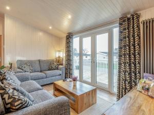 ein Wohnzimmer mit Sofa und Tisch in der Unterkunft Heather Lodge in Willington