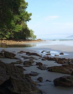 a beach with rocks and trees in the water at Casa Malu in Bertioga