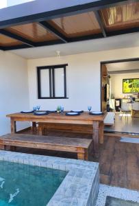 a living room with a wooden table and a swimming pool at Casa Malu in Bertioga