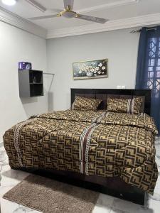 a bedroom with a bed with a brown and black comforter at Pat deluxe in New Weija