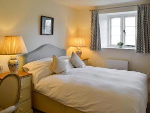 a bedroom with a white bed with two lamps and a window at The Coach House in Chulmleigh +21 photos