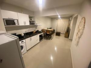 una cucina con armadi bianchi e un tavolo di Encantador apartamento de 2 dormitorios a Luque