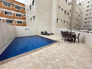 ein Swimmingpool in einem Gebäude mit Tisch und Stühlen in der Unterkunft Apto c/ vista mar e piscina no prédio perto do mar in Samaritá