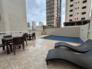 eine Dachterrasse mit einem Pool, Tischen und Stühlen in der Unterkunft Apto c/ vista mar e piscina no prédio perto do mar in Samaritá