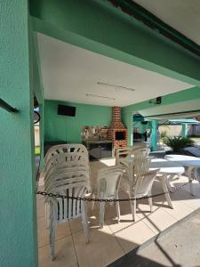 Un patio con sillas blancas y una mesa y una chimenea. en Acomodação Ideal Samambaia, en Ananindeua