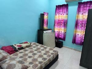 a bedroom with a bed and purple walls at Deena Homestay Seri Gading BP in Sri Gading