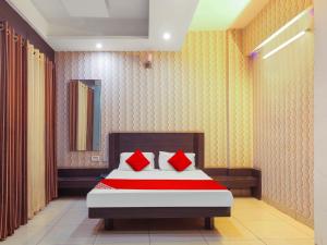 a bedroom with a bed with red pillows at Hotel O New Om Palace in Bhopal