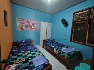 Dos camas en una habitación con paredes azules. en Home stay Mekman, en Tenganan