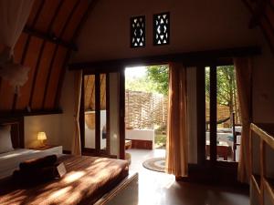 a bedroom with a bed and a sliding glass door at Rising Sun Bungalows in Gili Meno