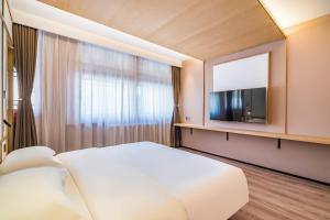 a bedroom with a large white bed and a tv at Floral Hotel Beijing Heyuan Courtyard Luxury Hotel in Beijing +43 photos