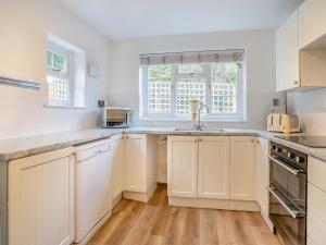 eine Küche mit weißen Schränken und einer Spüle in der Unterkunft The Retreat Cottage in Machen