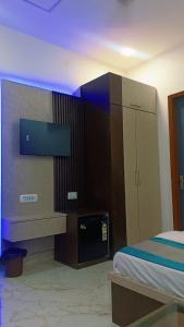 a bedroom with a bed and a dresser with a tv at Siddhi inn in Gangānagar