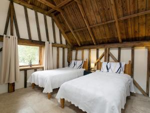two beds in a room with wooden ceilings at Chilsham Barn in Herstmonceux +34 photos