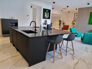 a kitchen with a island with a sink and two chairs at Appartement haut standing au cœur de Douai avec wifi, climatisation et terrasse - FR-1-510-235 in Douai +27 photos