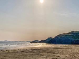 una playa con el sol saliendo sobre el agua en Snowdon House, en Porthmadog