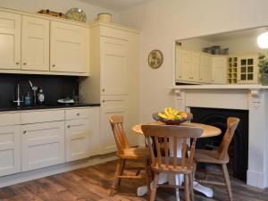 una cucina con mobili bianchi, tavolo e sedie di Clachries Cottage a Boreland of Colvend