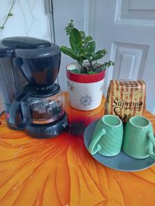 Una cafetera sobre una mesa con un plato y una planta. en Miliz City Center, en La Romana