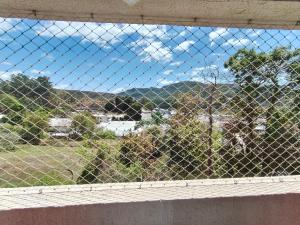 a view through a chain link fence of a field at Apartamento próximo ao shopping in Poços de Caldas