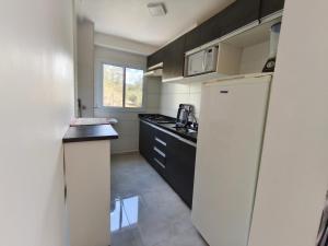 a small kitchen with a refrigerator and a counter at Apartamento próximo ao shopping in Poços de Caldas