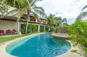 a swimming pool in front of a house at Stylish & Comfortable Condo with Balconies in Coco