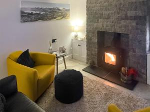 a living room with a yellow chair and a fireplace at Cosy Cottage in Portinscale