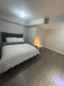 ein Schlafzimmer mit einem Bett und einem Tisch mit einer Lampe in der Unterkunft Beautiful&Spacious 2 Bedroom Basement Family Suite in Bradford