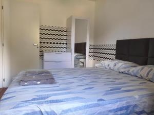 a bedroom with a large bed with a blue comforter at Apartamento próximo ao shopping in Poços de Caldas