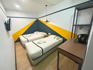 two beds in a small room with a desk at Seeds Hotel Bukit Bintang in Kuala Lumpur
