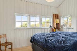 a bedroom with a bed and two windows at Family House With Sea View In Svinkløv in Andrup