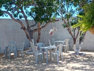 a group of tables and chairs in front of trees at Pensionado Mami Tchesca in Aracati