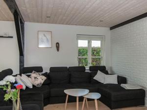 Una sala de estar con un sofá negro y una mesa. en 20 person holiday home in Ørsted, en Ørsted