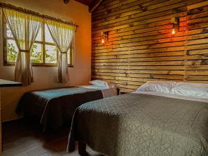 Un dormitorio con dos camas y una pared de madera. en Cabaña Xamixkali, en Zacatlán