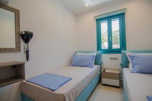 a room with two beds with blue pillows and a window at Ios Sea View in Ios Chora