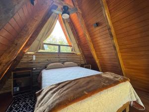 a bedroom in a log cabin with a bed and a window at Cabaña Tlazocalli in Zacatlán