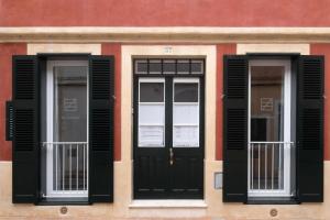 een gebouw met twee ramen en een zwarte deur bij Hotel Ca S'Arader Turismo de Interior in Ciutadella