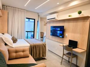 a hotel room with a bed and a desk with a laptop at Flat em Porto de Galinhas com Varanda, Aconchegante, Próximo ao Mar e ao Centro Comercial in Porto De Galinhas