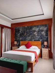 a bedroom with a bed and two tables and two lamps at Casa Green Kori in Kerobokan +2 photos