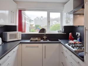 a kitchen with white cabinets and a sink and a window at Polperro in Keswick