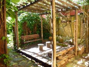 a wooden pergola with a bench in a garden at Maresias Hostel & Suites in Maresias