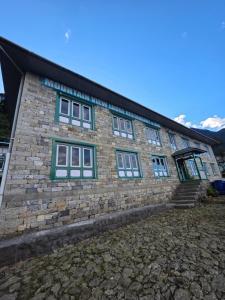 a large brick building with green windows on it at Mountain View Lodge in Lukla +29 photos
