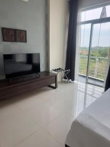 Un dormitorio con TV de pantalla plana y una ventana grande. en Executive Apartment at Cinta Sayang Club, en Sungai Petani