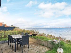 a table and chairs with a view of the water at 4 person holiday home in Middelfart-By Traum in Middelfart +24 photos
