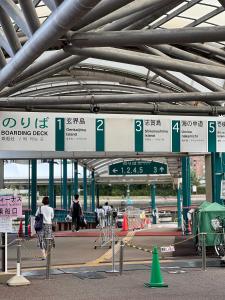 Una estación de tren con carteles y gente caminando. en Fukuoka tenjin house 福岡博多区天神 一戸建て, en Fukuoka