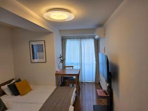 東京にあるホテルレスポワール301のベッド、テーブル、テレビが備わる客室です。