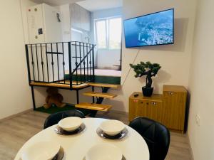 Una habitación con una mesa y sillas y un televisor. en The Union Square Apartament, en Oradea