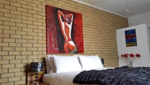 a bedroom with a bed and a painting on a brick wall at Mountain View Country Estate in Parys