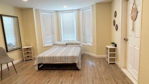 a bedroom with a bed in a room with windows at Classical Isbills Row House close to NYC in Bayonne