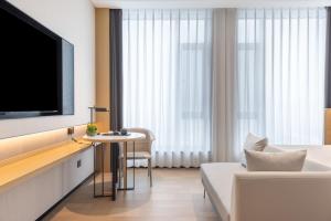 a hotel room with a tv and a couch and a table at Jinyi Select Hotel Hohhot Juhaicheng International Convention and Exhibition Center in Hohhot +7 photos