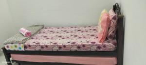 a small bed with pink sheets and pillows on it at Bait al-Qamar in Kampong Wakaf Tengah