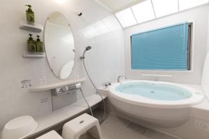 a bathroom with a tub and a sink and a mirror at Sommelier Villa ISHIGAKI in Ishigaki Island